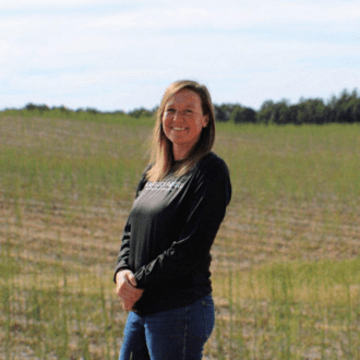 Woman in a black long-sleeve shirt and jeans standing in a field