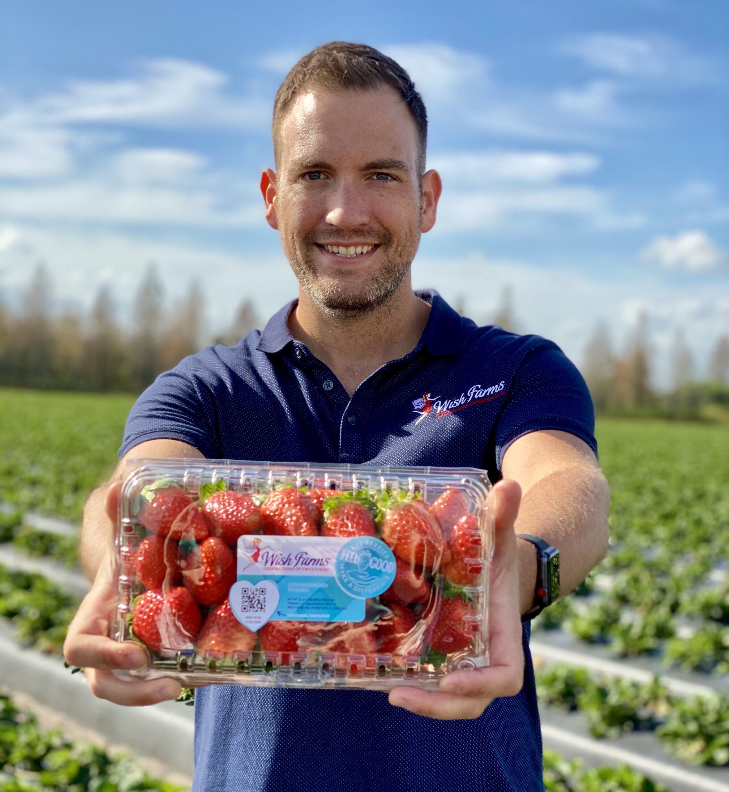 White man holding a package of strawberries in a field