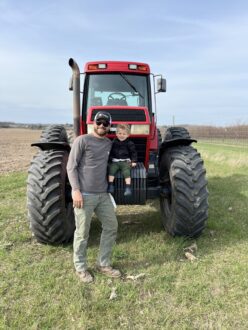 Talon Felker and son Casen in front of a tractor.