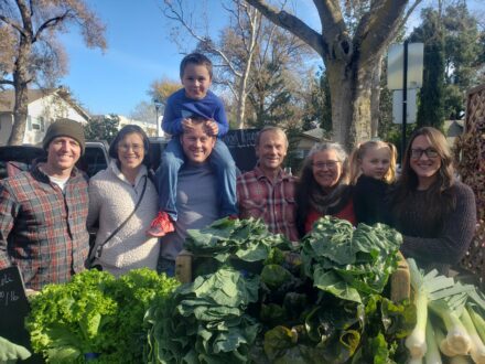 Good Humus Produce’s family members in front of leafy greens.