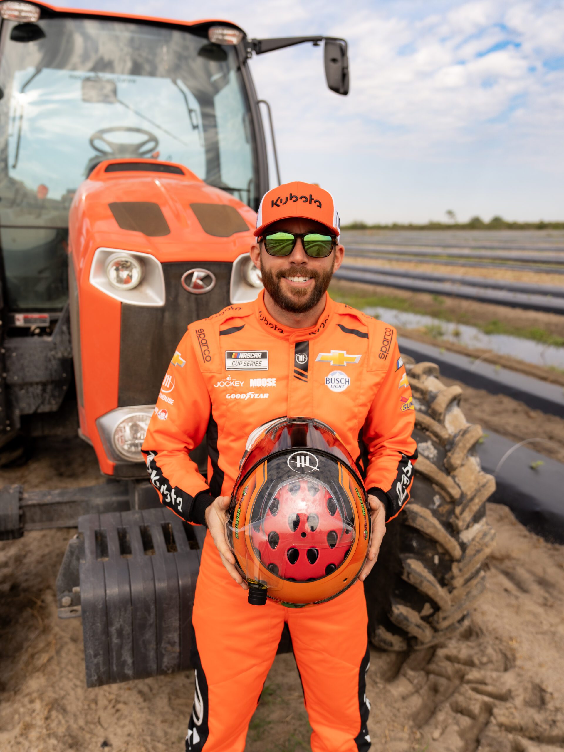 NASCAR racer and watermelon grower Ross Chastain in a field in front of a tractor.