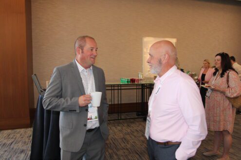 Two men talking with each other at the USApple Outlook conference in Chicago.