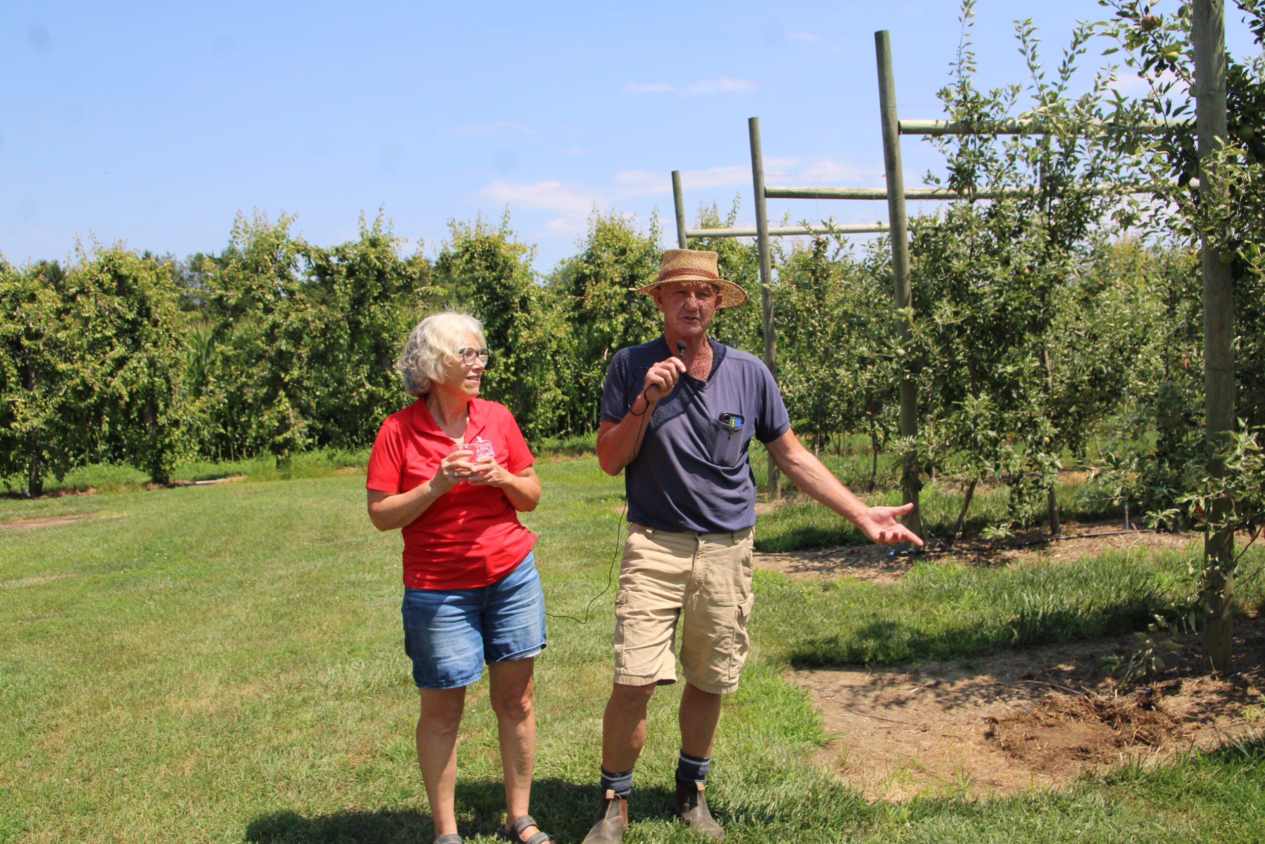 Photo of The Fruit Wagon’s Leslie and “Farmer Doug” Balsillie discussing cider apple and peach production in an orchard.