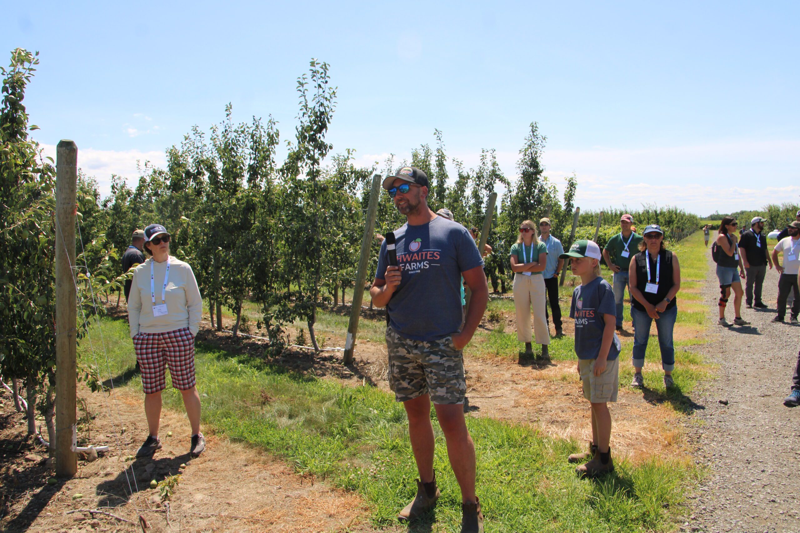 Photo of Nelson Thwaites of Thwaites Farms discussing pear and peach production with his son Lincoln in an orchard
