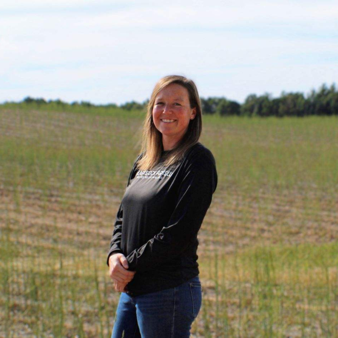 Woman in a black long-sleeve shirt and jeans standing in a field