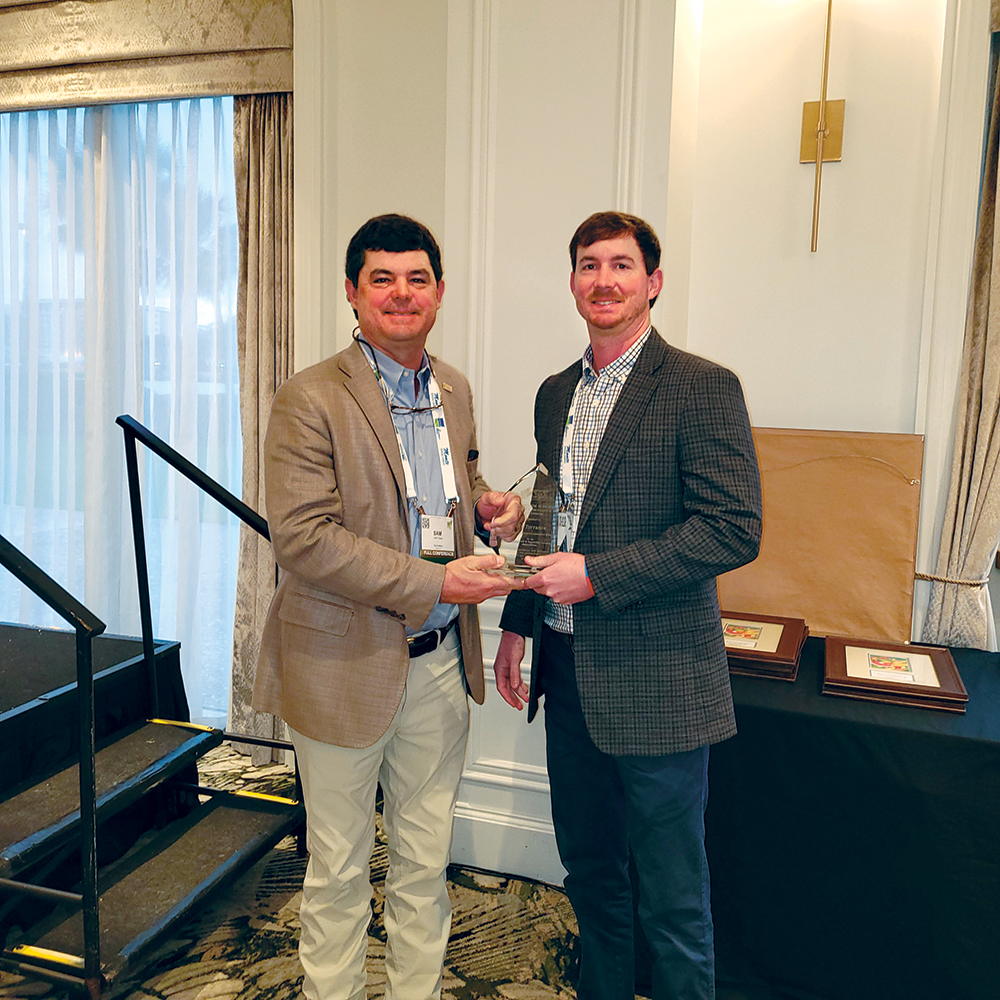 Sam Watson, left, and Ty 
Torrance, right, holding a glass award between them