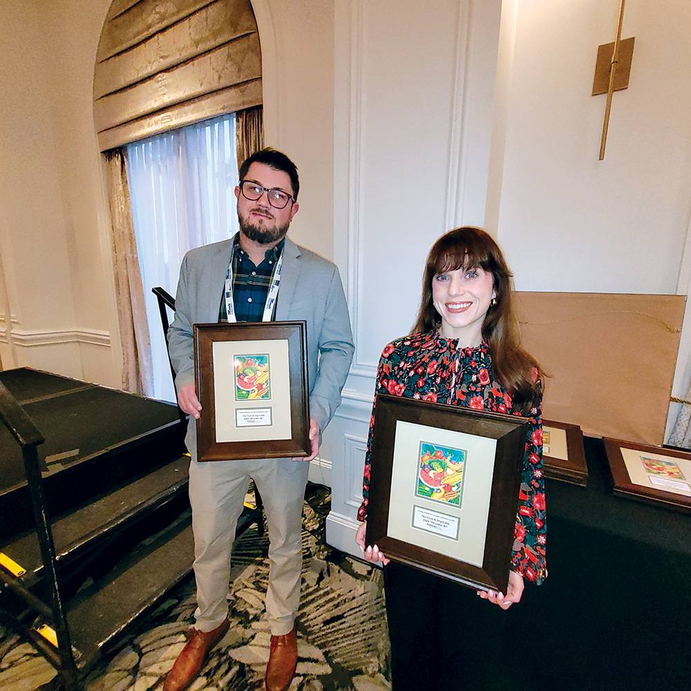 A man, left and a woman, right, both holding framed awards