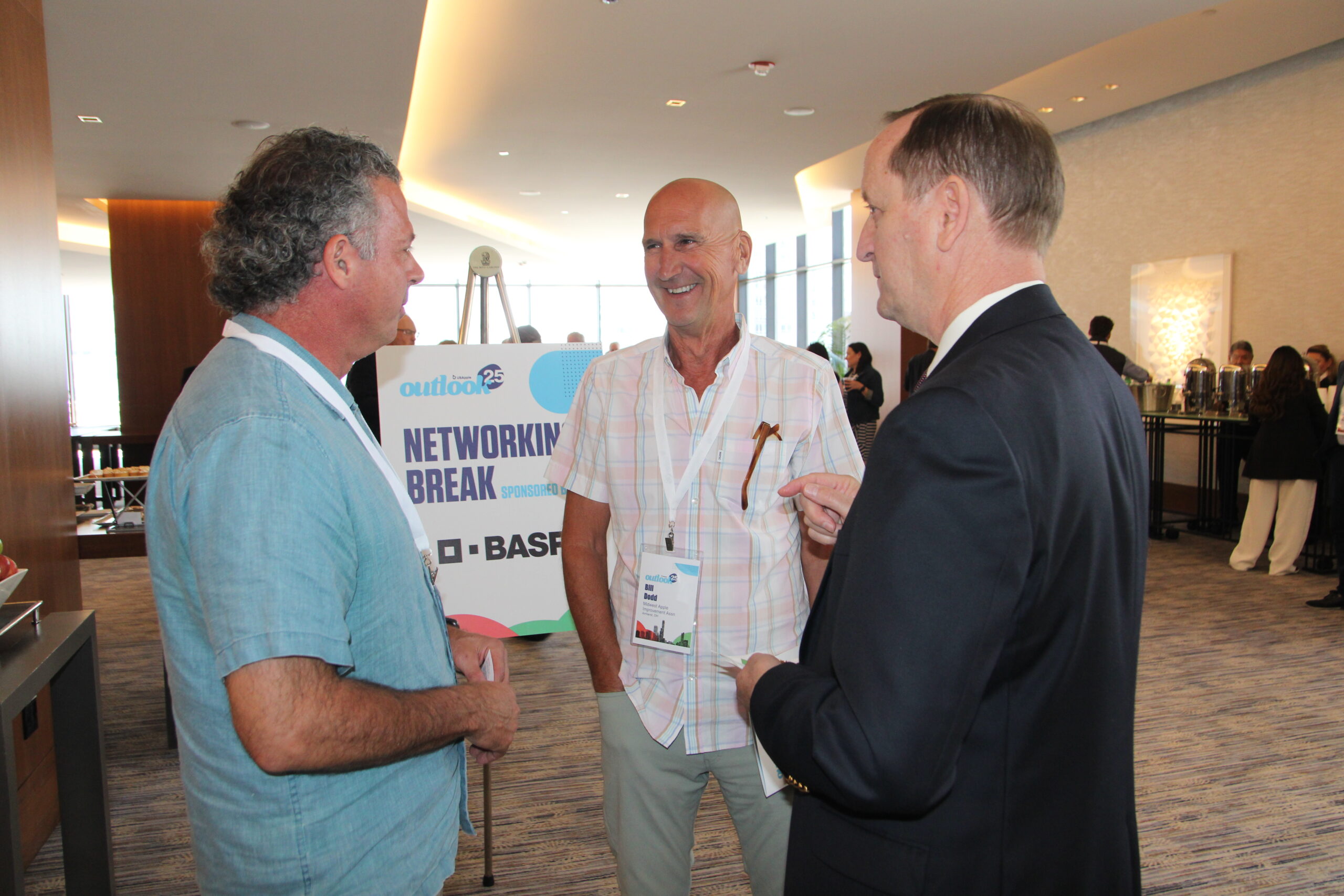 Three men talking with each other at the USApple Outlook conference in Chicago.