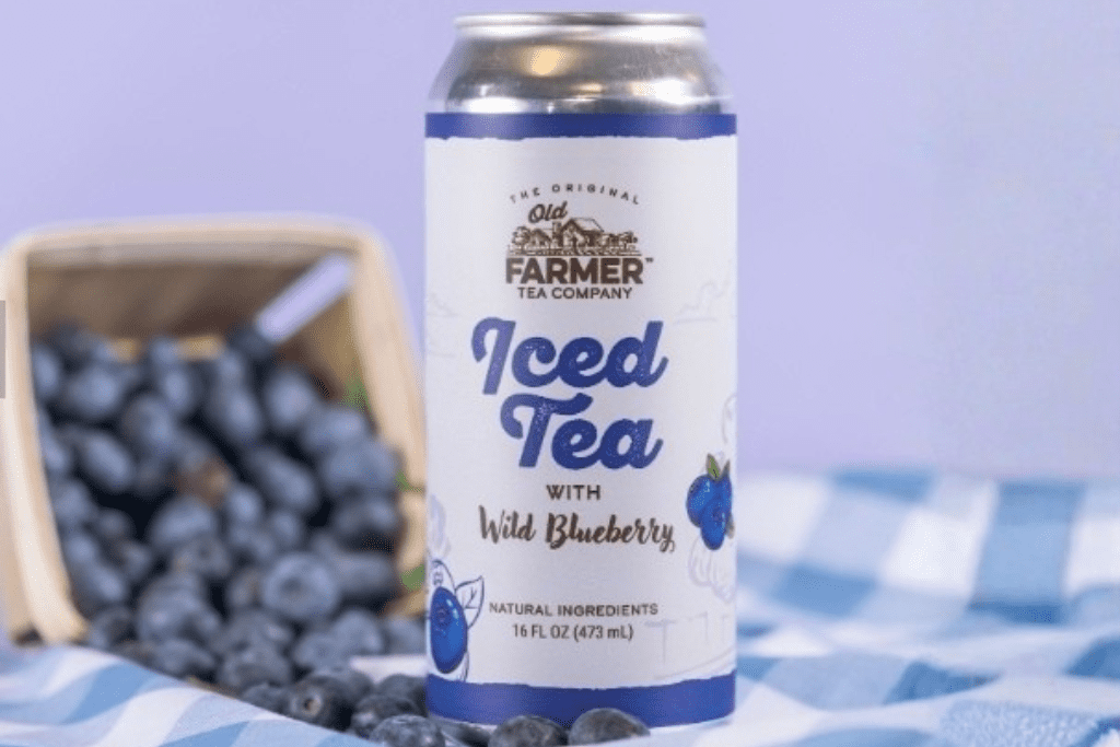 Image of a can of Iced tea in front of a box of blueberries, which are spilling out on the table